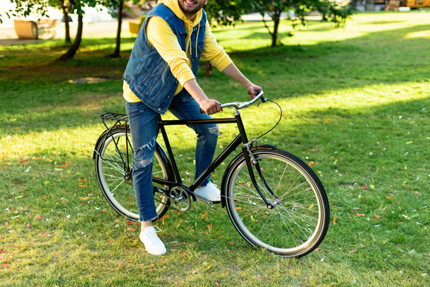 partial view of man stylish man riding retro bicycle in park - Fotó, kép