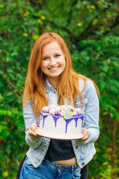 偉大なケーキに彼女の手でカメラのレンズと笑顔に見えるかわいい女の子 - 写真・画像
