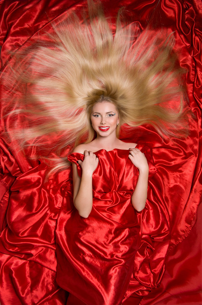 ξανθιά με μακριά μαλλιά σε κόκκινο ύφασμα - Φωτογραφία, εικόνα
