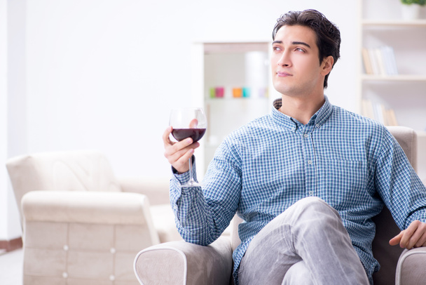 Young man drinking wine at home - Фото, зображення