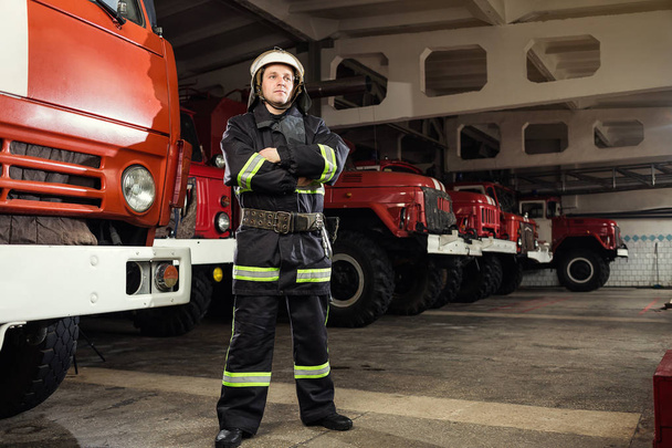 Bombero (bombero) en acción de pie cerca de un camión de bomberos. Seguridad de emergencia. Protección, rescate del peligro
. - Foto, Imagen