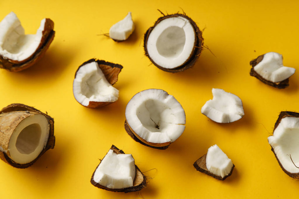 delicious fresh coconut halves and pieces on yellow background, top view   - Fotoğraf, Görsel