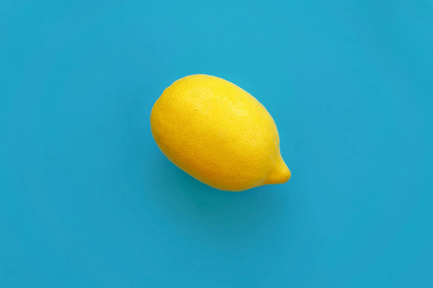 zářivě žlutý citron na modrý papír ležel. pohled shora na módní stylové pozadí, ovoce. prostor pro text - Fotografie, Obrázek