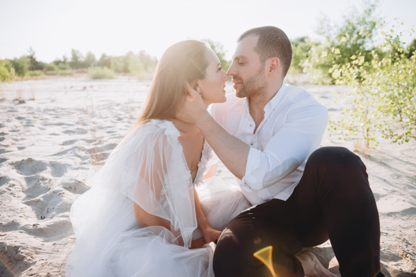 happy tender couple going to kiss while sitting on beach - Fotografie, Obrázek