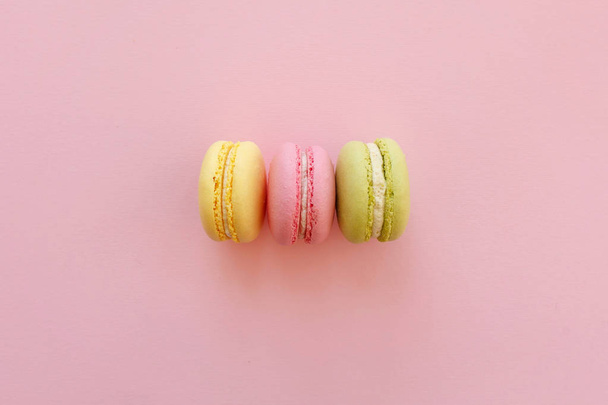 food photography flat lay of tasty colorful macarons  on trendy pastel pink paper. space for text pink, yellow, green macaroons. yummy background. diet concept. luxury catering - Фото, зображення