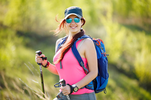 Photo of smiling female athlete with walking sticks and backpack with blurred background - Foto, Imagem