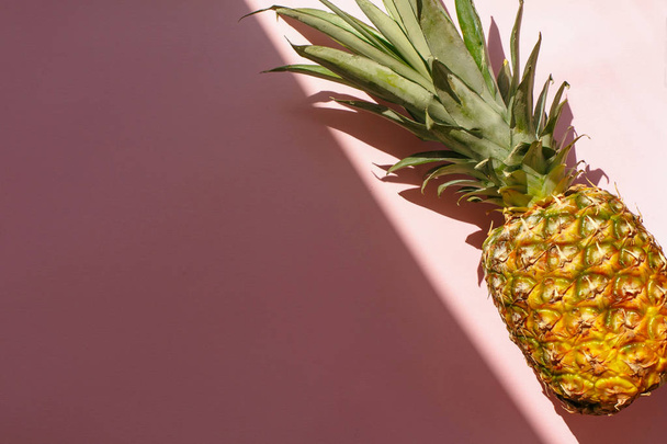 juicy pineapple on trendy pink paper background in sun light. flat lay. creative contrast summer image. vacation and party concept. space for text. tropical summer holidays - Photo, Image