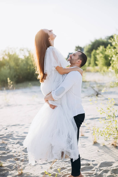 handsome man holding his happy girlfriend on hands on beach - Fotografie, Obrázek