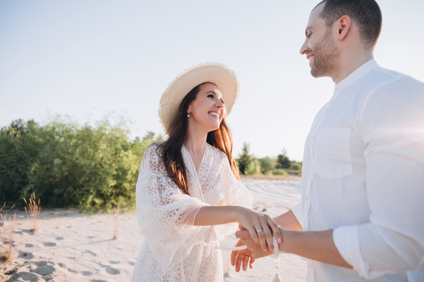 beautiful young smiling couple holding hands on beach - Foto, afbeelding