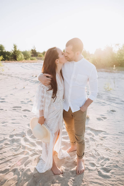 happy couple hugging and kissing on beach with backlit - Φωτογραφία, εικόνα