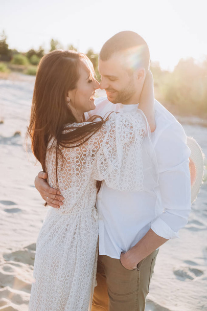 beautiful smiling couple embracing on beach with sunlight - Zdjęcie, obraz