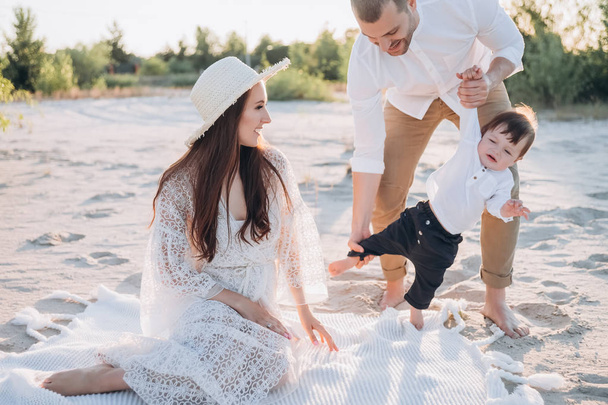 boldog szülők birtoklás móka-val imádnivaló baba fiú strandon - Fotó, kép