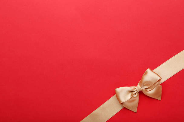 Golden bow with ribbon on red background - Fotó, kép