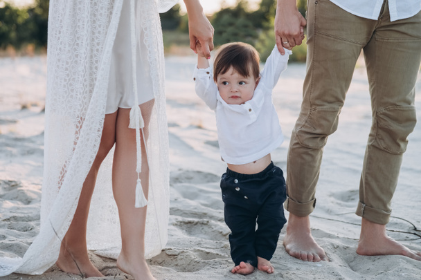 junge Familie hält Händchen mit entzückendem Sohn am Strand - Foto, Bild