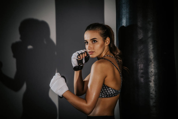 young beautiful girl boxer in a dark gym - Fotó, kép