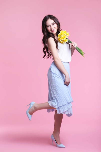 young woman with narcissus flowers on pink background  - 写真・画像