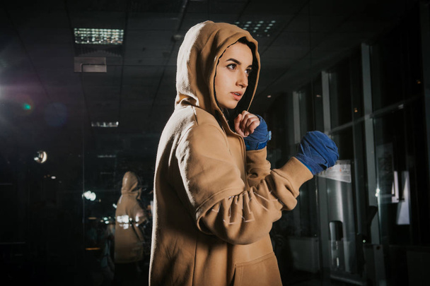 young beautiful girl boxer in a dark gym - Фото, изображение