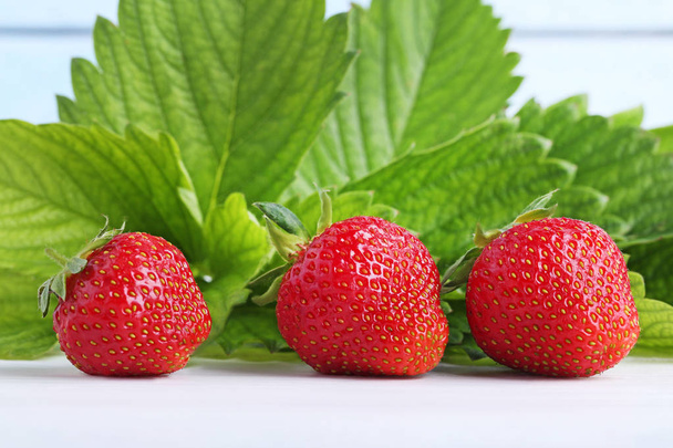 Fresh strawberries with green leafs on white wooden table - Foto, Imagem