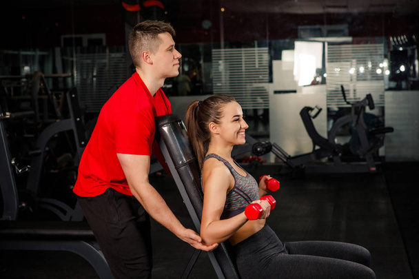 young beautiful couple sportsmen in sportswear doing exercises in a dark gym - Photo, Image