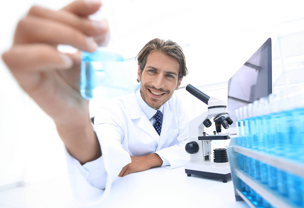 Portrait of a chemist holding a tube with liquid. - Фото, изображение