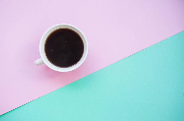 A cup of fresh black coffee on pink and green background with text space. - Photo, Image
