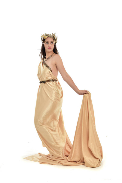 full length portrait of brunette woman wearing gold grecian gown, standing pose. isolated on white studio background. - Fotó, kép