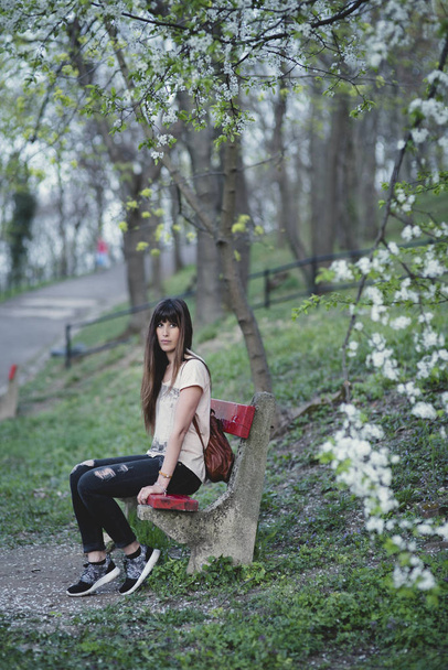 piękna młoda kobieta na zewnątrz w parku. Kaukaski dziewczyny o długich brązowych włosach siedzi w ławce w romantycznej pozie - Zdjęcie, obraz