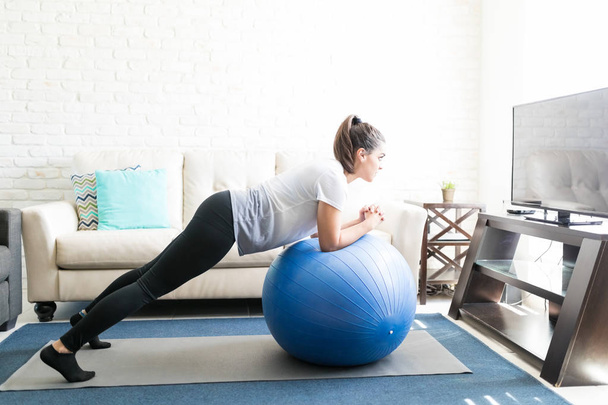 junge lateinische Frau macht Core Stretch Workout mit Pilates Ball - Foto, Bild