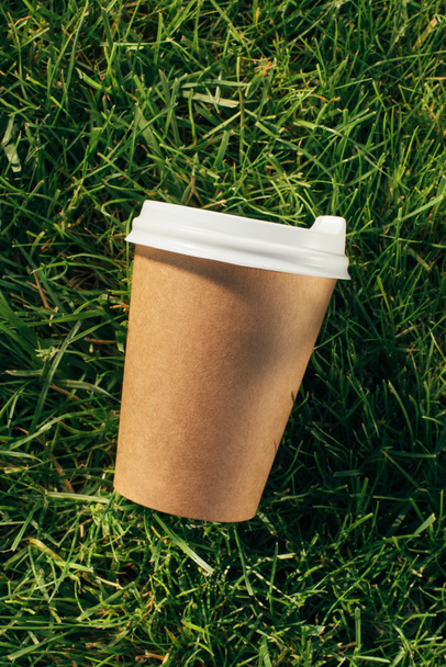 top view of disposable cup of coffee on green grass - Fotó, kép