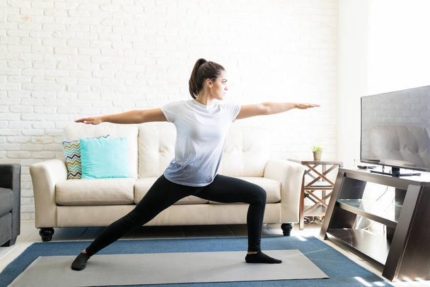 Ajuste joven mujer en yoga guerrero pose en casa
 - Foto, imagen
