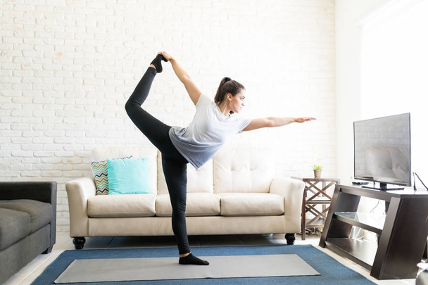 junge Frau im Wohnzimmer übt sich in Tanz-Yoga-Pose - Foto, Bild
