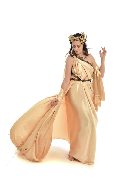 full length portrait of brunette woman wearing gold grecian gown, standing pose. isolated on white studio background. - Fotografie, Obrázek
