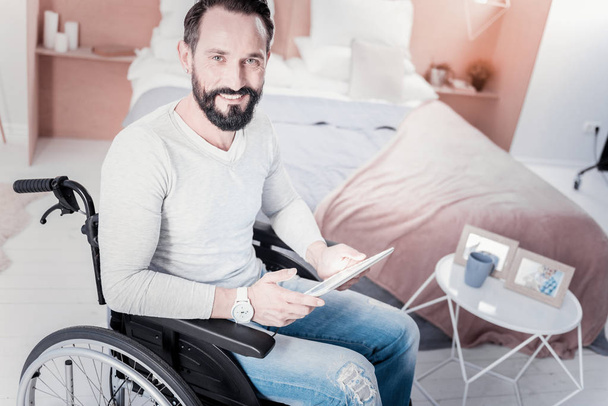 Content crippled man holding a tablet - Foto, afbeelding