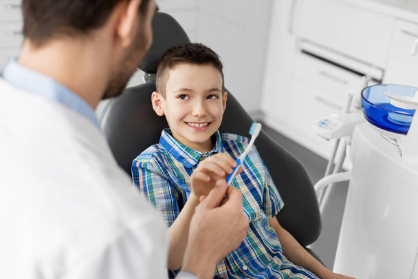 стоматолог, дающий зубную щетку ребенку в клинике
 - Фото, изображение