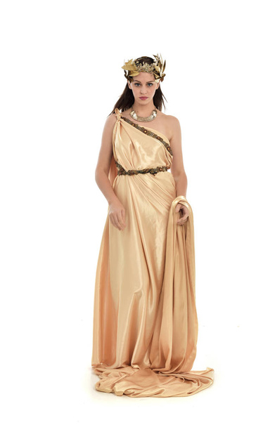 Ολόσωμο πορτρέτο μελαχρινή γυναίκα φοράει χρυσά grecian εσθήτα, όρθια στάση. απομονωμένα σε φόντο λευκό στούντιο. - Φωτογραφία, εικόνα