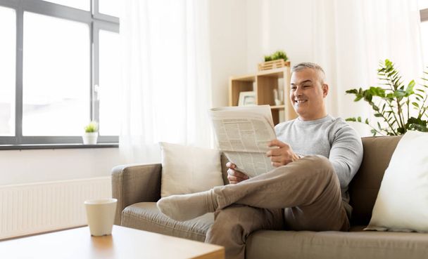 happy man reading newspaper at home - Fotó, kép