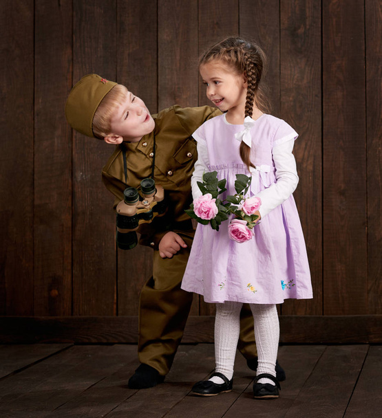 chłopiec dzieci są ubrani jak żołnierz w retro mundury wojskowe i dziewczyna w różowej sukience - Zdjęcie, obraz