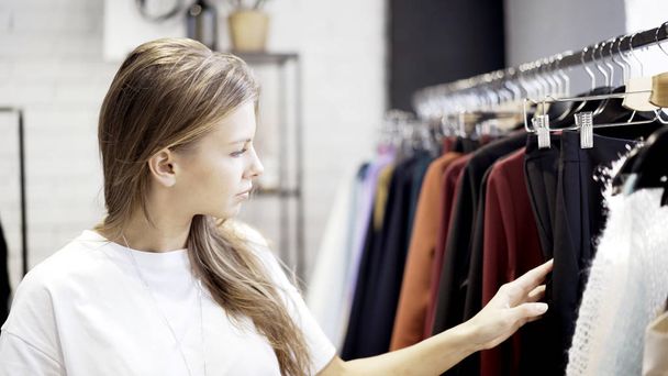 A young pretty girl is shopping in a clothing store - 写真・画像