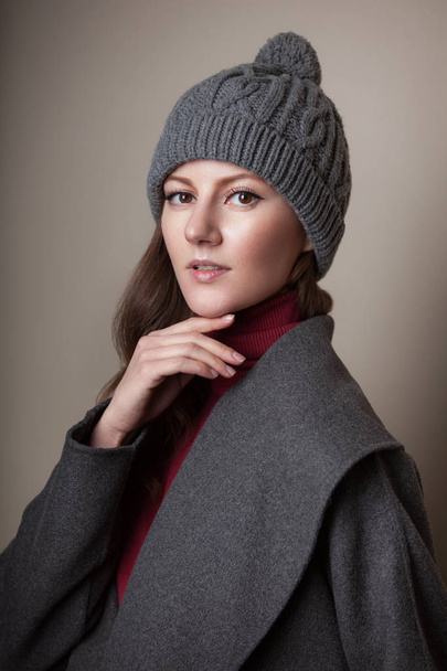 retrato de alta moda de mujer joven elegante abrigo gris al aire libre y sombrero de otoño de invierno en estudio sobre fondo marrón gris
 - Foto, Imagen