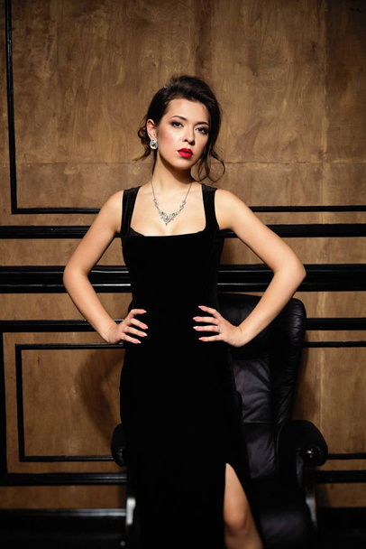 Gorgeous young brunette woman in elegant black dress posing - Foto, imagen