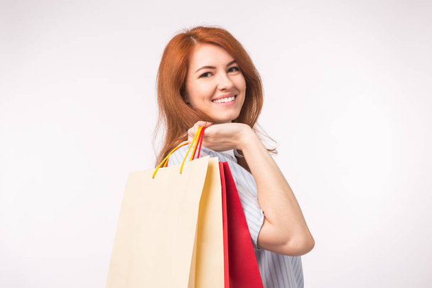 Porträt einer jungen glücklichen rothaarigen Frau mit Einkaufstaschen auf weißem Hintergrund - Foto, Bild