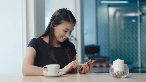Smiling pretty woman texting on smartphone in a cafe - Photo, image