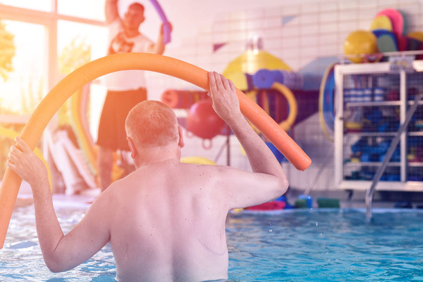 Csoport- vagy fiatal és idős emberek aquarobic fitness medence gyakorlása során - Fotó, kép