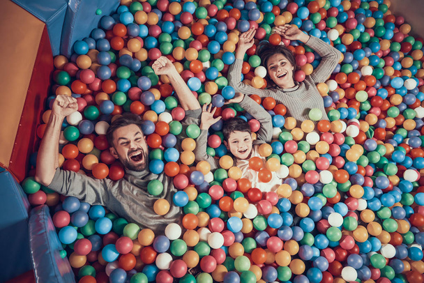 Top view. Happy family lying in pool with balls. Family rest, leisure concept. Spending holiday together. Entertainment center, mall, amusement park. - Fotó, kép