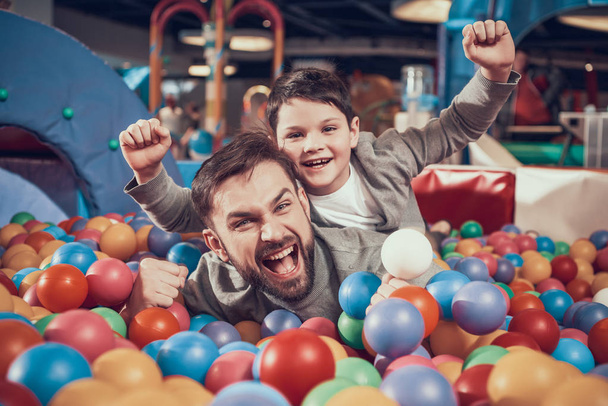Enjoying dad and son in pool with balls. Family rest, leisure. Spending holiday together with family. Entertainment center, mall, amusement park. - Fotó, kép