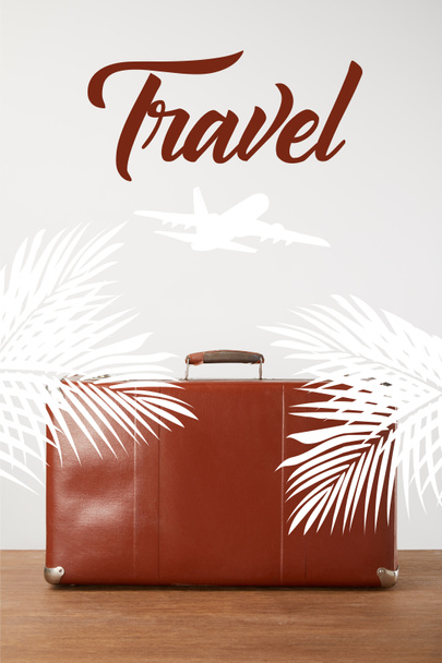 Maleta de cuero marrón vintage con hojas de palma, avión y letras de viaje
 - Foto, Imagen
