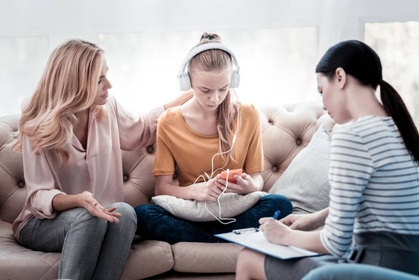 Chica nerviosa escuchando música durante la cita psicológica
 - Foto, imagen