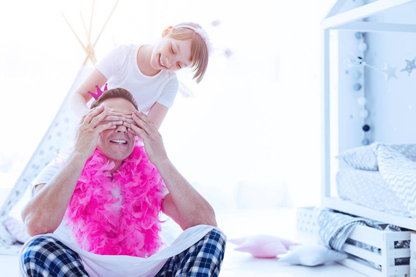 Cheerful girl closing eyes of daddy while playing - 写真・画像