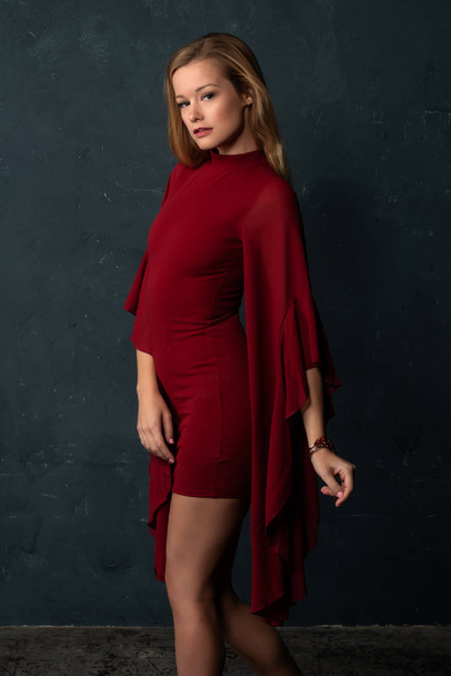 Alta rubia delgada en un vestido corto rojo con mangas voluminosas
 - Foto, Imagen