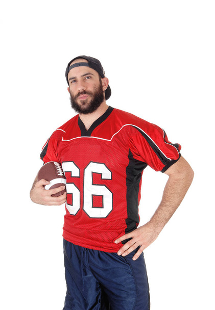 A football player in his red jersey and his brown football in his hand - Photo, Image